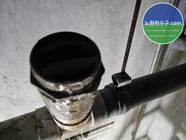벽을 따라 지나는 검은 배관의 청소구를 연 모습